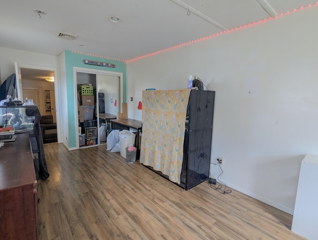 interior space with visible vents, baseboards, a closet, and wood finished floors