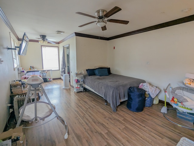 bedroom with visible vents, baseboards, wood finished floors, and ornamental molding