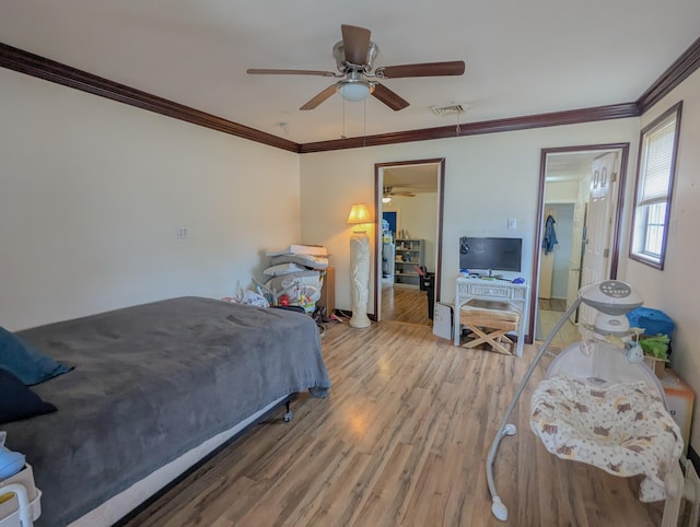 bedroom with visible vents, ornamental molding, a ceiling fan, and wood finished floors