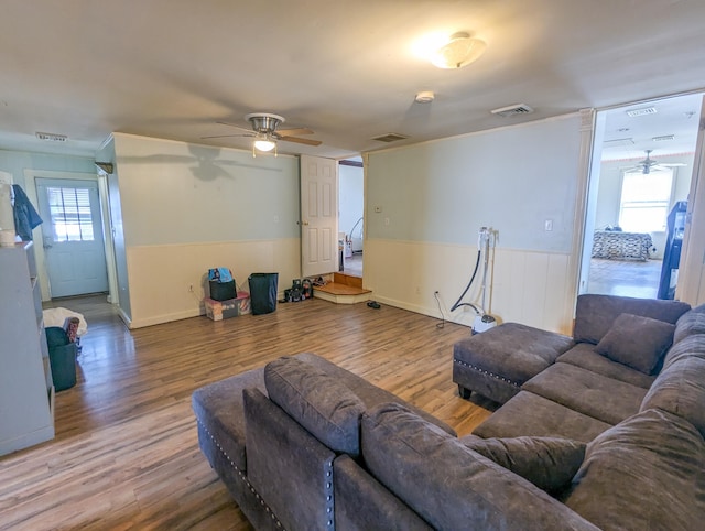 living area with visible vents, wainscoting, ceiling fan, and wood finished floors