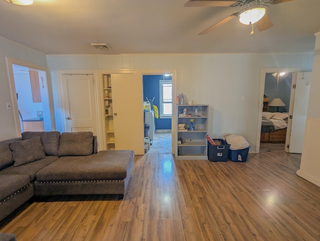 living area featuring crown molding, wood finished floors, visible vents, and ceiling fan