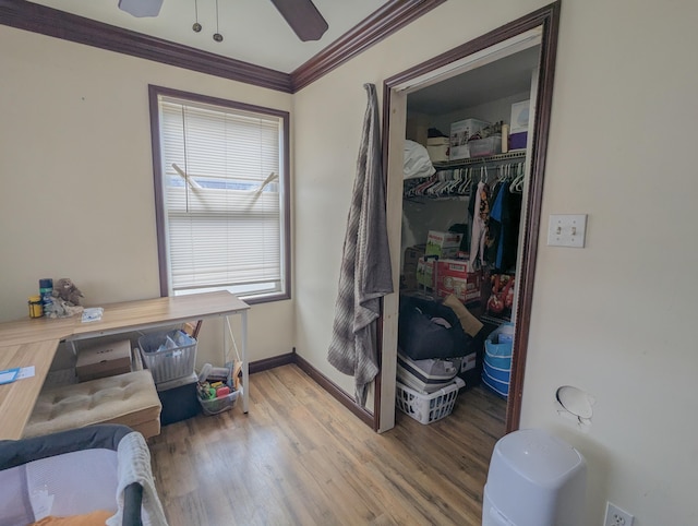 bedroom with wood finished floors, a closet, crown molding, baseboards, and ceiling fan