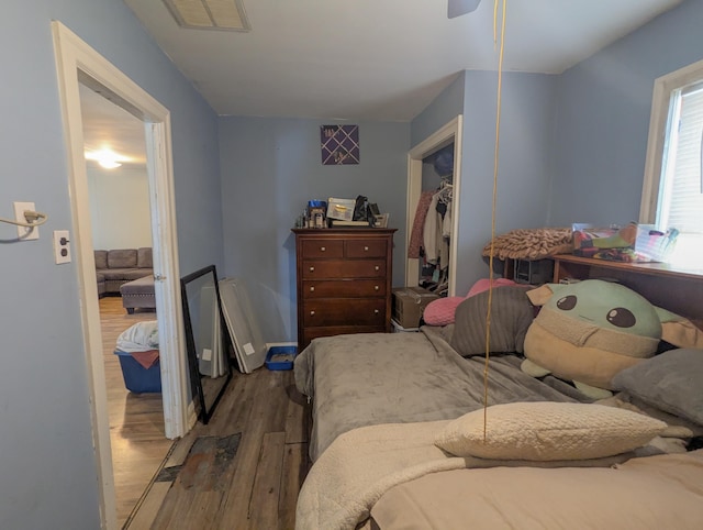 bedroom featuring wood finished floors, visible vents, and a closet