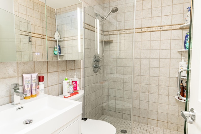 bathroom featuring a shower with door, vanity, and toilet