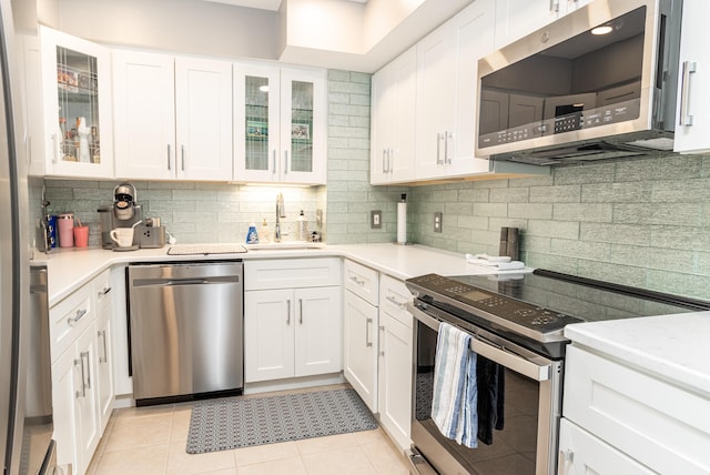 kitchen with white cabinets, appliances with stainless steel finishes, sink, and light tile patterned flooring