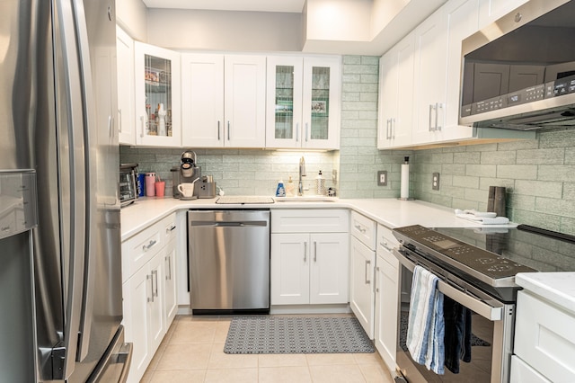 kitchen featuring sink, white cabinets, light tile patterned floors, and appliances with stainless steel finishes