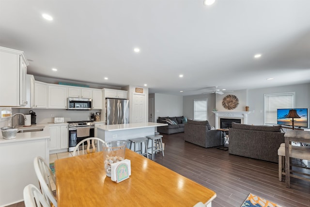 dining space with wood finished floors, a glass covered fireplace, a ceiling fan, and recessed lighting