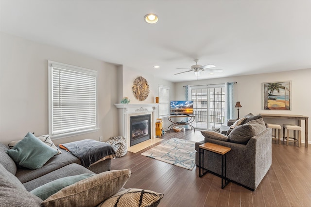 living area featuring a fireplace with flush hearth, recessed lighting, a ceiling fan, and wood finished floors