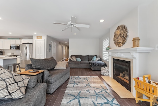 living room featuring a ceiling fan, recessed lighting, a tile fireplace, and wood finished floors