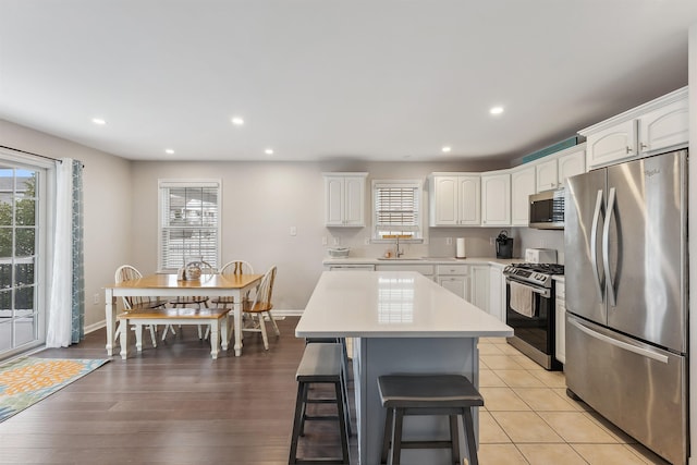 kitchen featuring a center island, light countertops, appliances with stainless steel finishes, white cabinets, and a sink