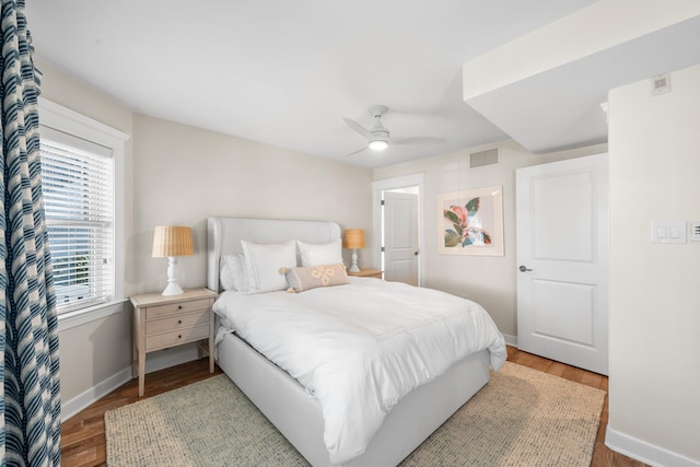 bedroom featuring a ceiling fan, baseboards, visible vents, and wood finished floors