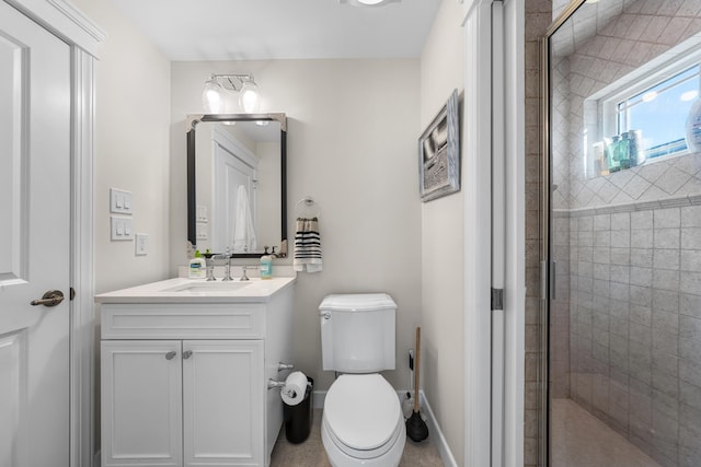 full bath with a stall shower, vanity, toilet, and baseboards