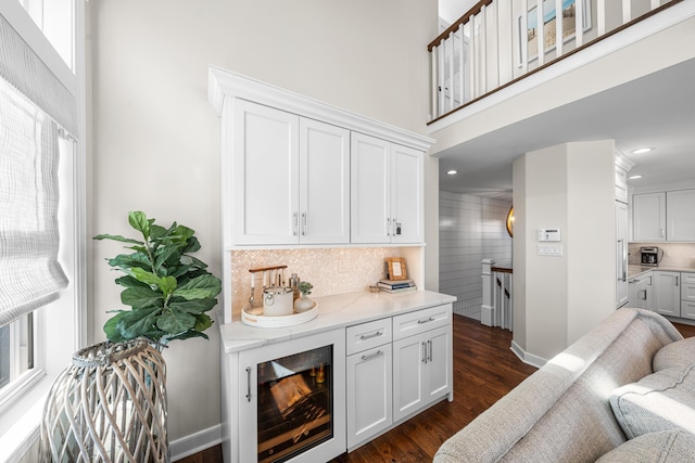 living room with a towering ceiling, baseboards, dark wood finished floors, and recessed lighting