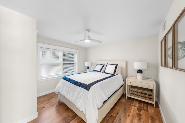 bedroom featuring visible vents, ceiling fan, baseboards, and wood finished floors