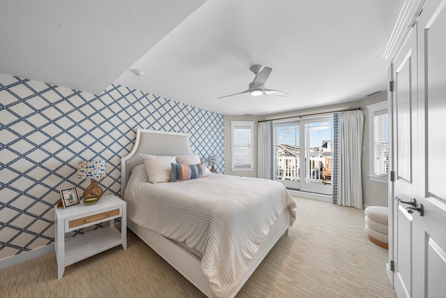 bedroom with light colored carpet, an accent wall, baseboards, access to outside, and wallpapered walls