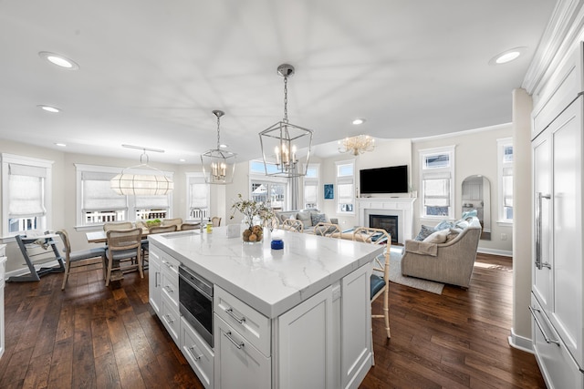 kitchen featuring stainless steel microwave, a kitchen breakfast bar, white cabinets, recessed lighting, and a kitchen island