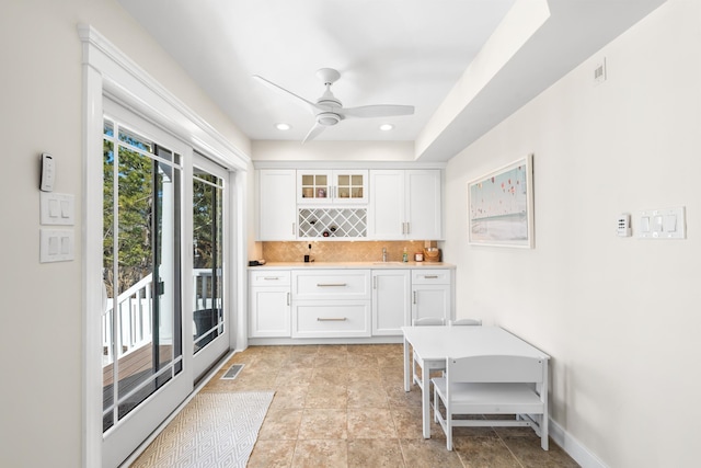 interior space featuring light countertops, tasteful backsplash, glass insert cabinets, and white cabinetry