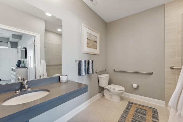 bathroom featuring toilet, visible vents, vanity, baseboards, and tiled shower