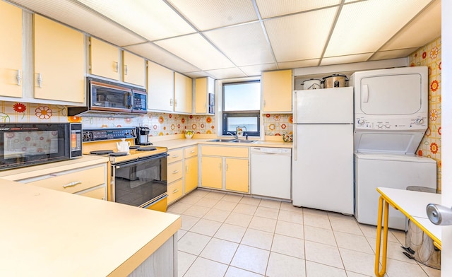 kitchen with light countertops, white appliances, stacked washer and dryer, and a sink