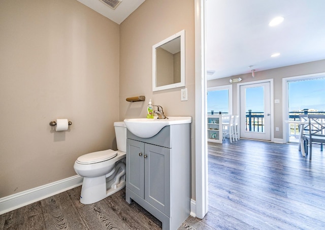 bathroom featuring toilet, wood finished floors, visible vents, vanity, and baseboards