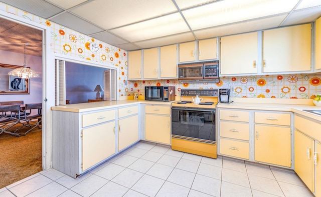 kitchen with black microwave, light countertops, electric range oven, and light tile patterned flooring