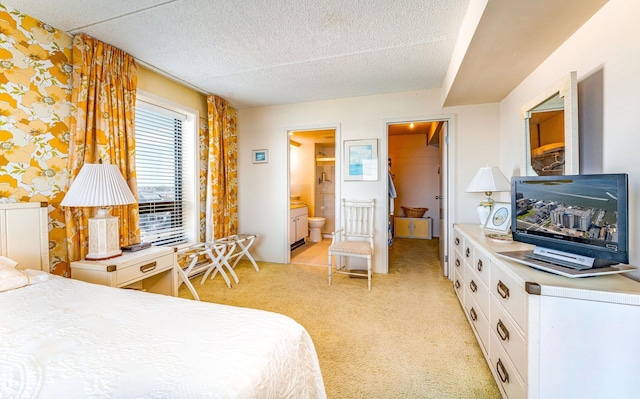 bedroom with light carpet, a textured ceiling, and ensuite bath