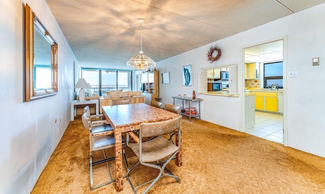 dining space featuring light carpet and a notable chandelier