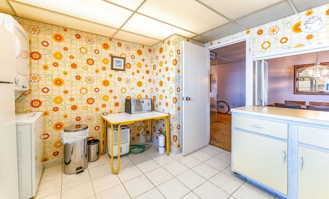 bathroom featuring stacked washer and dryer, a paneled ceiling, and tile patterned floors