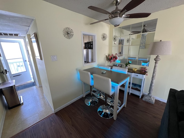 dining room featuring ceiling fan, a textured ceiling, and dark hardwood / wood-style floors