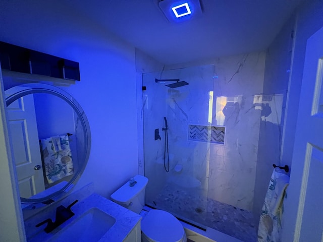 bathroom featuring toilet, vanity, and tiled shower