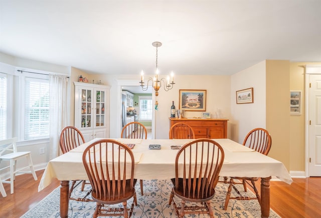 dining space featuring light wood-style flooring, baseboards, and a notable chandelier