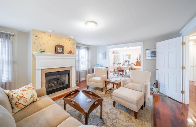 living area with a fireplace with raised hearth and wood finished floors