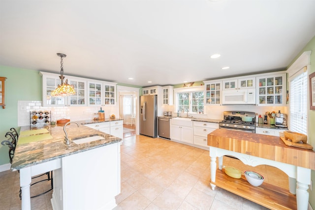 kitchen featuring tasteful backsplash, appliances with stainless steel finishes, white cabinets, a sink, and a peninsula