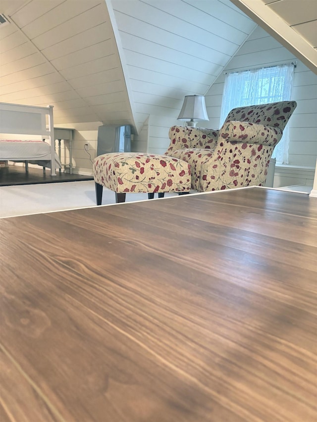 additional living space featuring lofted ceiling and wood walls