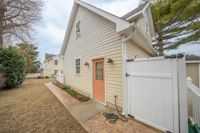 exterior space with a gate, fence, and a lawn