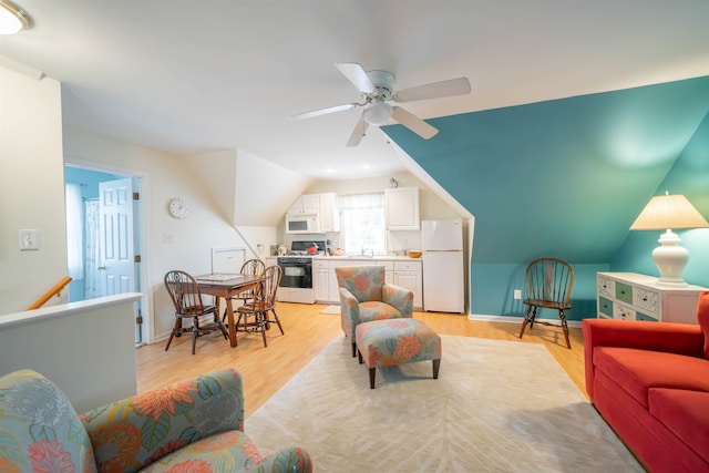 living area featuring light wood-type flooring, ceiling fan, baseboards, and vaulted ceiling