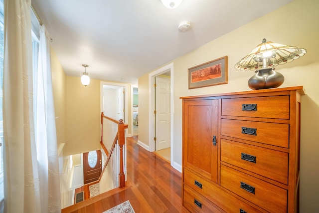 hall featuring wood finished floors, an upstairs landing, and baseboards