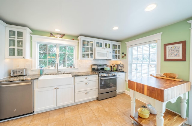 kitchen featuring stone counters, stainless steel appliances, backsplash, white cabinets, and a sink