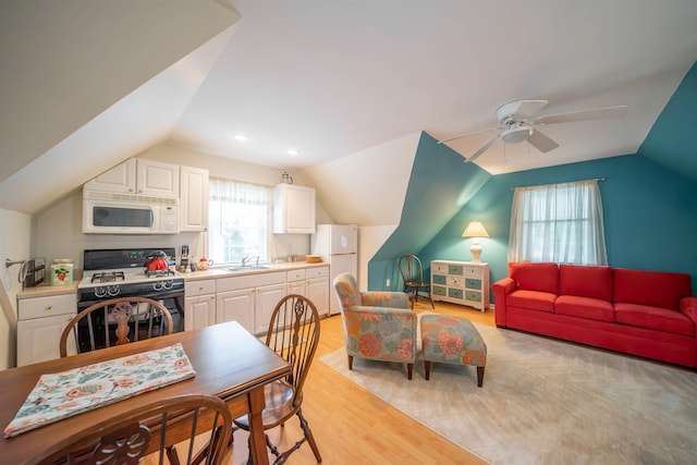 kitchen featuring white appliances, lofted ceiling, light wood-type flooring, white cabinetry, and a sink