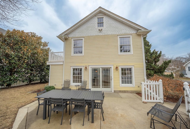 back of house featuring a balcony, outdoor dining space, fence, and a patio