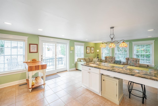 kitchen featuring decorative light fixtures, visible vents, white cabinetry, dark stone countertops, and baseboards