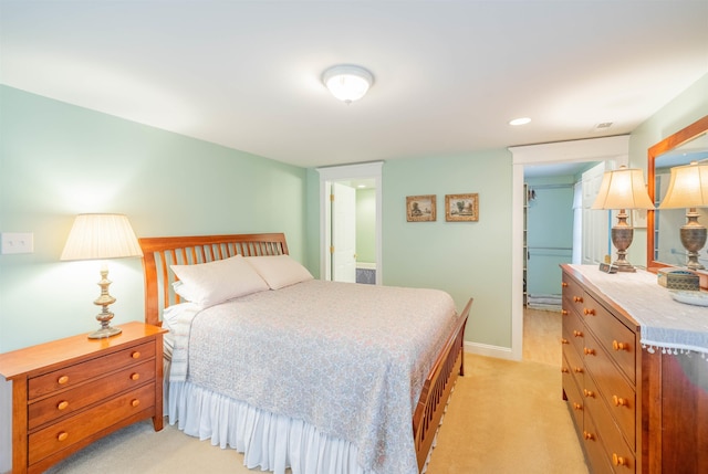 bedroom featuring a walk in closet, a closet, light carpet, and baseboards