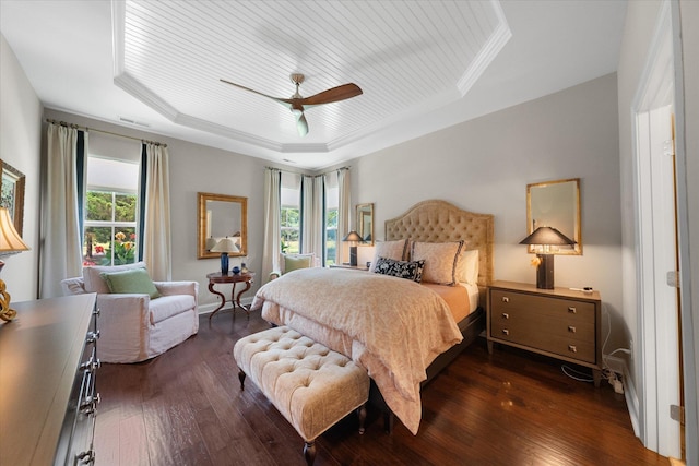 bedroom with ceiling fan, dark hardwood / wood-style floors, crown molding, and a tray ceiling