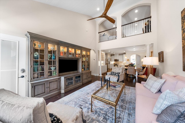 living room featuring dark hardwood / wood-style floors, ceiling fan, and a towering ceiling