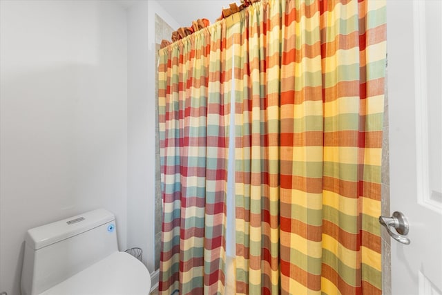 bathroom featuring a shower with curtain and toilet