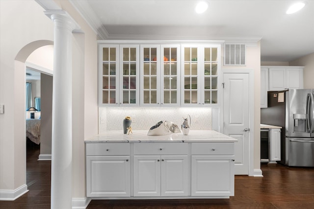 bar with backsplash, light stone countertops, white cabinetry, dark hardwood / wood-style flooring, and stainless steel fridge with ice dispenser