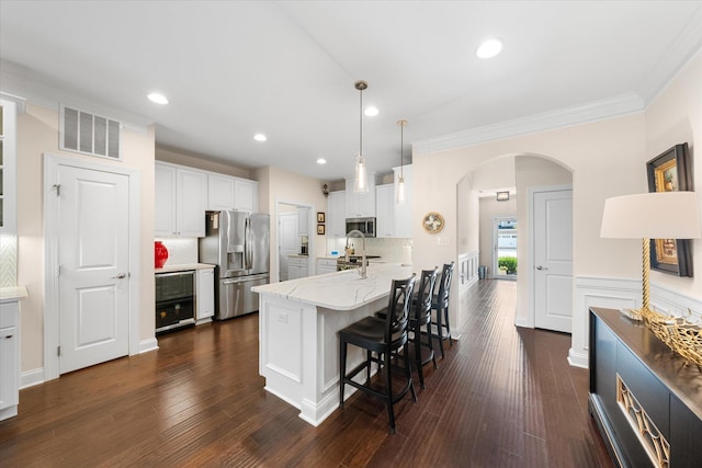 kitchen with a kitchen bar, appliances with stainless steel finishes, kitchen peninsula, pendant lighting, and white cabinets