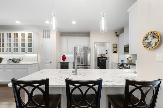 kitchen with washer / dryer, decorative backsplash, white cabinets, and appliances with stainless steel finishes