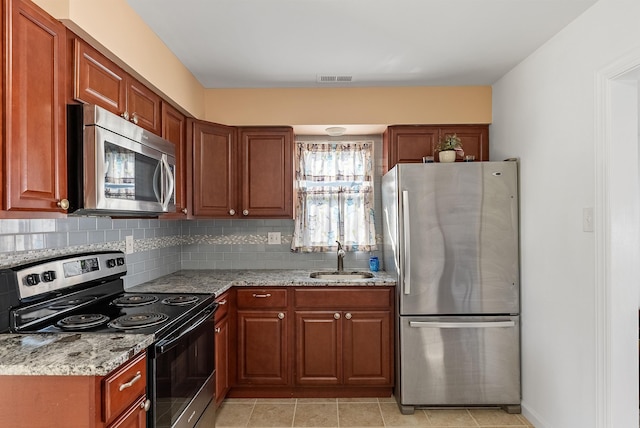 kitchen featuring tasteful backsplash, light stone counters, stainless steel appliances, a sink, and visible vents