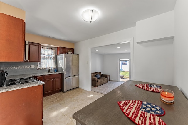 kitchen with a healthy amount of sunlight, a sink, decorative backsplash, and freestanding refrigerator